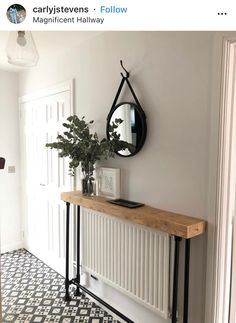 a wooden table sitting under a mirror on top of a wall next to a plant