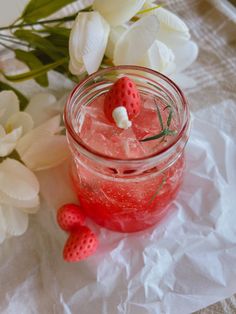 a jar filled with ice and strawberries next to flowers