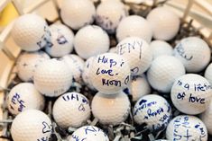 a basket filled with lots of white golf balls covered in blue writing on each ball