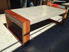 a coffee table made out of wood and concrete with a shelf on the bottom that is built into it