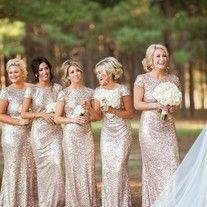 a group of women standing next to each other in front of some trees and grass