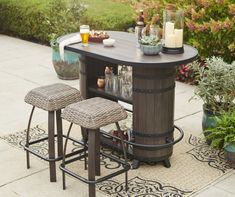 an outdoor bar with two stools next to it and some drinks on the table