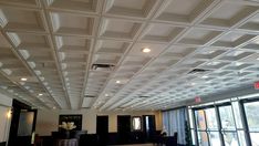 an empty room with large windows and white ceiling tiles on the ceiling is lit by recessed lights