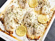 fish with lemons and herbs on a baking sheet, ready to be cooked in the oven