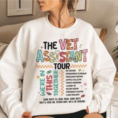 a woman wearing a white sweatshirt with the vet assistant tour written on it