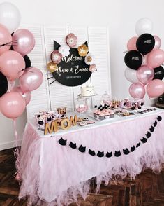 a table topped with lots of pink and black balloons