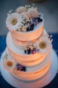 a three tiered wedding cake with flowers and eggs on top is lit up at night