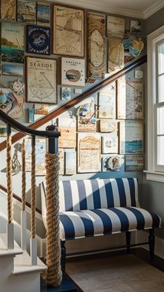 a striped bench sitting under a stair case next to a wall covered with pictures and postcards