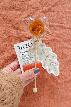 a person holding a candy lollipop with a leaf shaped stick attached to it