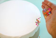 a person is decorating a cake with sprinkles