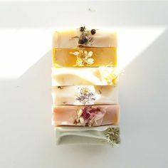 three soap bars with flowers on them sitting on a white counter top next to a bee