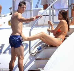 a man and woman in swimsuits sitting on a boat with other people around them