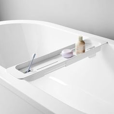 a bathtub with toothbrushes and soap in it next to a white tub