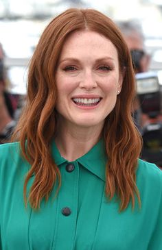 a woman with red hair is smiling at the camera while she stands in front of photographers