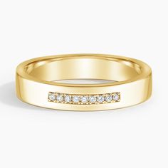 a yellow gold wedding band with channeled diamonds on the outside, set against a white background