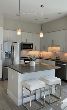 a kitchen with two stools next to an island in the middle of the room