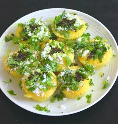 a white plate topped with cupcakes covered in toppings on top of a table