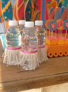 three plastic water bottles with tassels on them and candy sticks in the background