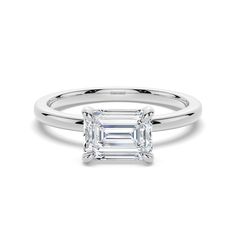 an emerald - cut diamond ring on a white background, with the center stone set in 18k white gold