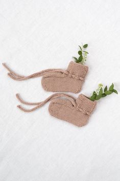 two knitted mittens with plants growing out of them on a white sheeted surface