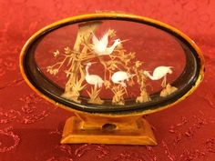 a glass display case with birds and flowers in it on a red tableclothed surface