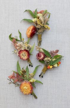 three different types of flowers are arranged on a white tablecloth with green leaves and red berries