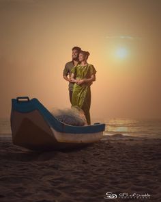 a man and woman standing on the beach next to a boat with sand in it