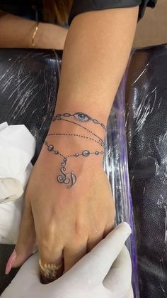 a woman's hand with a tattoo on it and an eye charm around the wrist