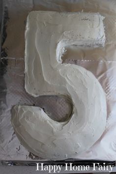 a cake that is shaped like the number five on a sheet of tin foil with white frosting