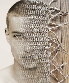 a man with his face covered by a piece of cloth next to a wooden fence