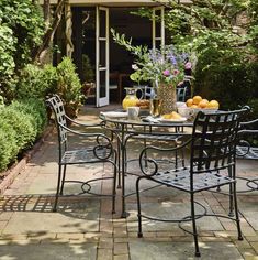 an outdoor table and chairs with fruit on it in the middle of a patio area