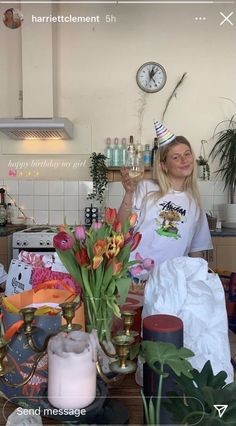 a woman standing behind a table with flowers and candles