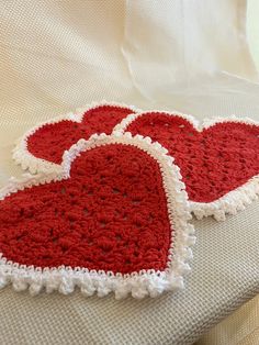 two crocheted hearts sitting on top of a bed