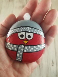 a hand holding a painted rock with an angry bird on it