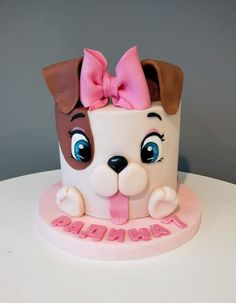 a birthday cake with a dog's face on it and pink ribbon around the top