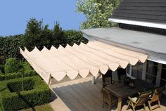 an awning on the roof of a house with a table and chairs in front of it