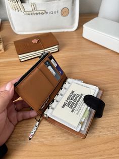 a person is holding a wallet and taking notes out of it on a table next to a stack of books