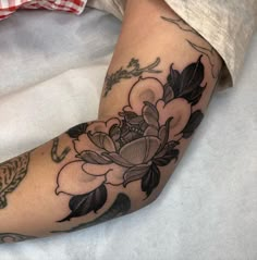 a woman's arm with flowers and leaves tattooed on the side of her leg