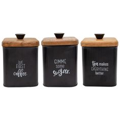 three black canisters with wooden lids and writing on the front one says, but first coffee