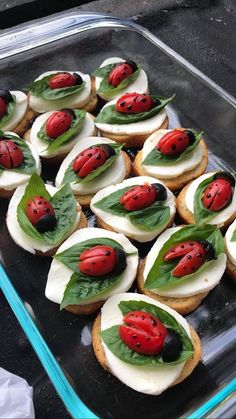 ladybugs on top of cream cheese and leaves in a glass baking dish, ready to be eaten