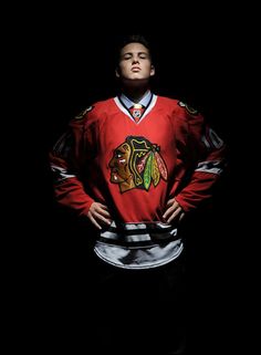 a man in a chicago black hawks jersey is standing with his hands on his hips