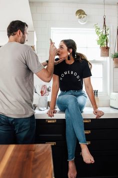 a man and woman in the kitchen brushing their teeth