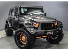 a gray jeep with orange accents is parked in a garage