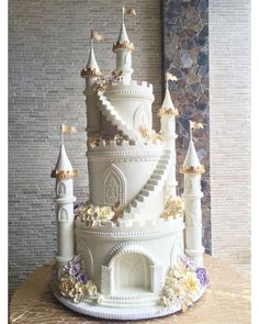 a large white cake decorated with flowers and castle like decorations on top of a table