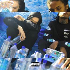 two men sitting next to each other with water bottles in front of them and one man wearing a black hoodie