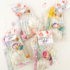 four little mermaids are packaged in plastic bags with tags on them and some candy