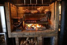 an open fire in a brick oven with meat cooking on the grill and wood burning inside