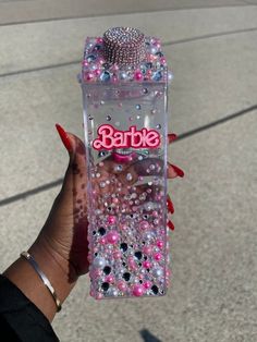 someone holding up a barbie bottle with pink and blue beads on the bottom that says barbie