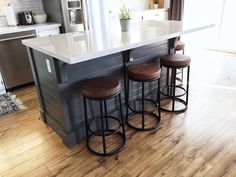 a kitchen island with three stools next to it