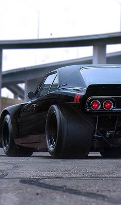 an image of a car that is on the road with big wheels and tires in front of a bridge